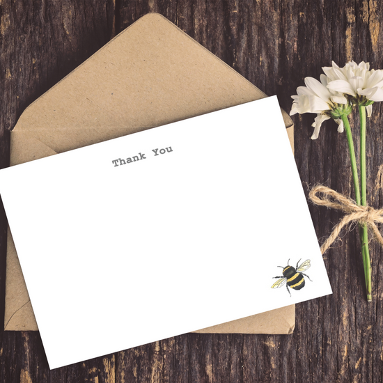 a card with a bee on it next to a flower